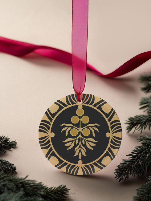 Round metal ornament featuring golden juniper berry branch design with Art Deco-inspired geometric border on black background. 3.5-inch diameter piece with botanical motif and crimson ribbon. Double-sided detailed artwork.